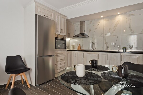 A modern kitchen with a built-in oven, stainless steel refrigerator, and marble backsplash.
