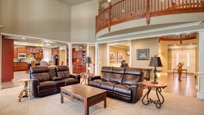 A spacious living area with a high ceiling, a wooden staircase, and a kitchen in the background. - Luxury Family Retreat w/ Views, Golf: Fore Seasons (Pinetop)
