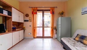 Una habitación con una cama, un refrigerador, un armario de madera y una ventana con cortinas.