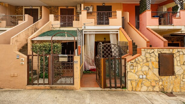 Una casa de dos pisos con un muro de piedra, un portón y una escalera.