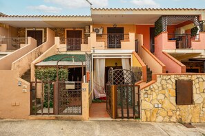 Une maison à deux étages avec un mur en pierre, un portail et un escalier.