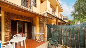 Un patio con una mesa, sillas, un muro de piedra y una valla de madera.