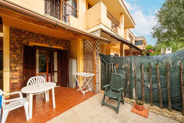 Une terrasse avec une table et des chaises, un mur en pierre et une clôture en bois.
