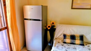 A white refrigerator, a sofa with a floral pattern, and a vase with sunflowers. - Holiday Home 'Pentagramma Apartment Villasimius' with Private Terrace and Wi-Fi (Villasimius)