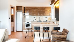 Una cocina moderna con una isla central, taburetes de bar y una zona de estar con sofá.