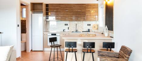 A modern kitchen with a central island, bar stools, and a seating area with a sofa.