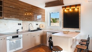Una cocina moderna con electrodomésticos integrados, una zona de comedor con taburetes y vistas a través de una ventana.