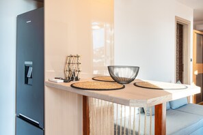 Une cuisine moderne dotée d’un réfrigérateur encastré, d’un plan de travail en bois et d’un coin salon avec un canapé bleu.