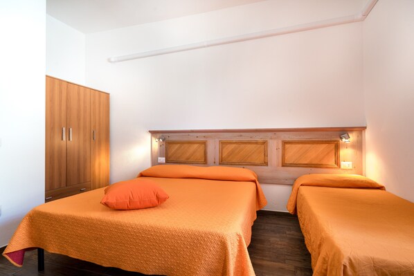 A room with two beds, wooden headboard, and a wardrobe.