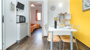 Een compacte keuken met een magnetron, een flatscreen-tv en een eethoek met een tafel en stoelen.