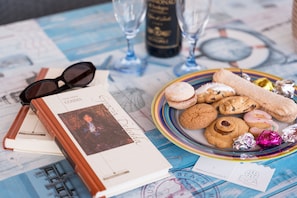 Una mesa con un libro, gafas, un plato de galletas y una botella.