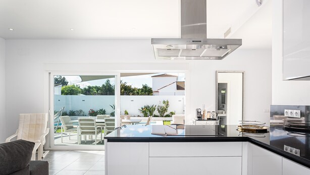 A modern kitchen with a central island, white cabinetry, and a stainless steel range hood.