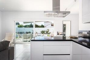 Une cuisine moderne dotée d’un îlot central, de meubles blancs et d’une hotte de cuisinière en acier inoxydable.