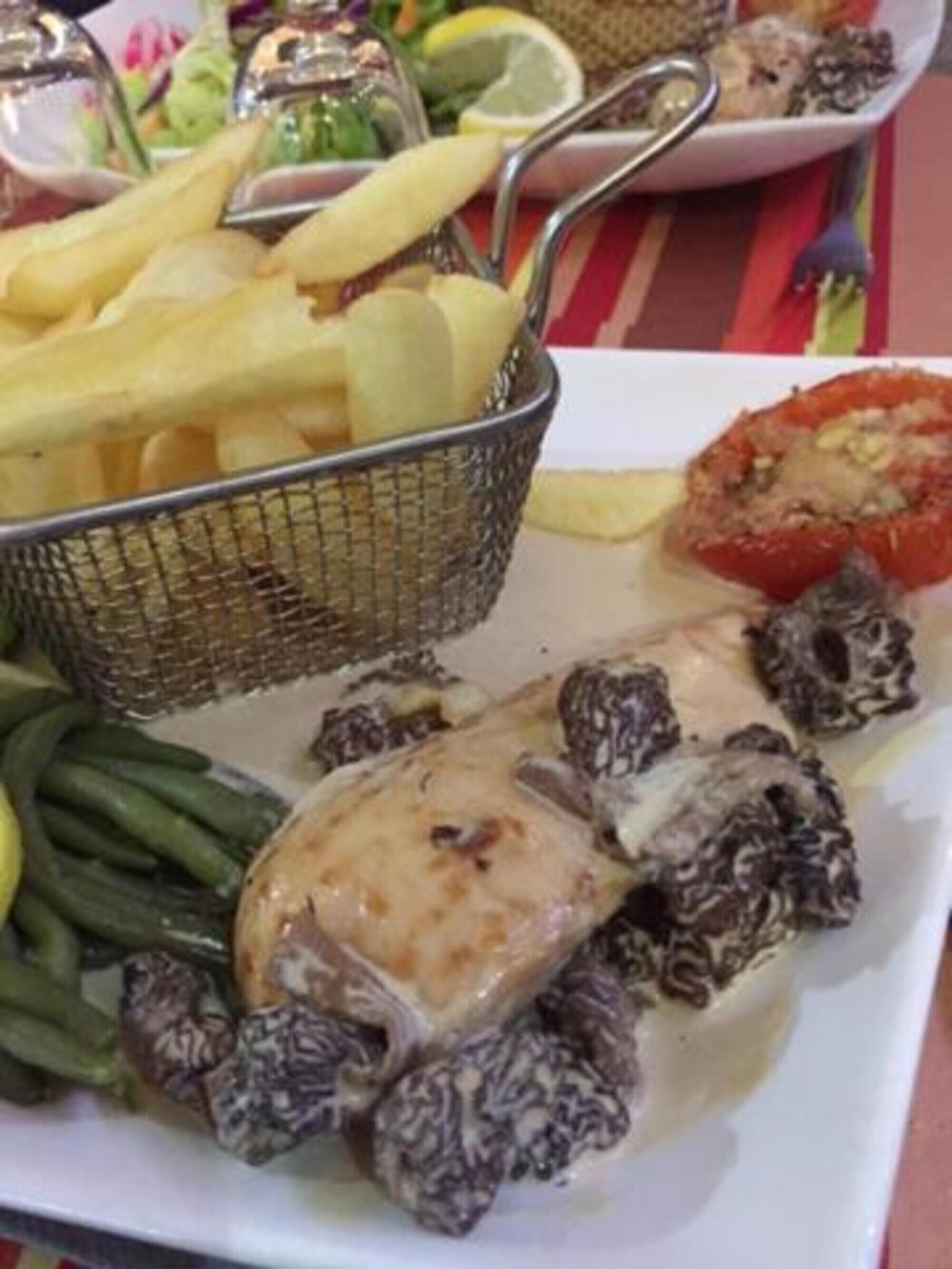 A plate with food items including a chicken leg, green beans, and a tomato.