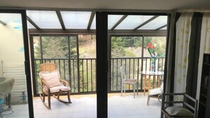 A balcony with a chair, a table, and a view of greenery. - Apartment 'Le Grenier D'annick' with Mountain View, Private Terrace and Wi-Fi (Villefort)