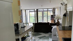 A kitchen with a dining area, a ceiling light, and a view through a glass door. - Apartment 'Le Grenier D'annick' with Mountain View, Private Terrace and Wi-Fi (Villefort)