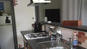 Een kleine keuken met een gasfornuis, twee spoelen, een koelkast en een magnetron.
