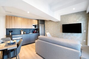 Una cucina moderna con elettrodomestici integrati, un'area pranzo con tavolo e sedie e un divano grigio.
