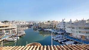 A marina with boats docked, a clear sky, and buildings with domed architecture.