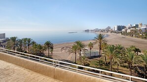 A coastal cityscape with a beach, palm trees, and buildings.