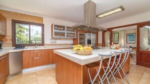 Eine Küche mit Kochinsel, Barhocker, einem Fenster und einem Kühlschrank.