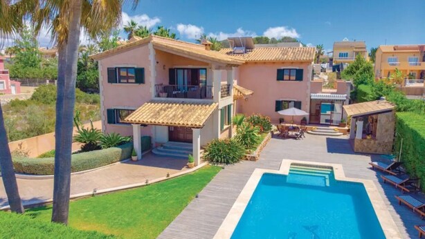 Ein zweistöckiges Haus mit Schwimmbad, Terrasse und kleinem Garten.