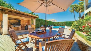 Eine Terrasse im Freien mit einem Holztisch, Stühlen und einem großen Sonnenschirm.