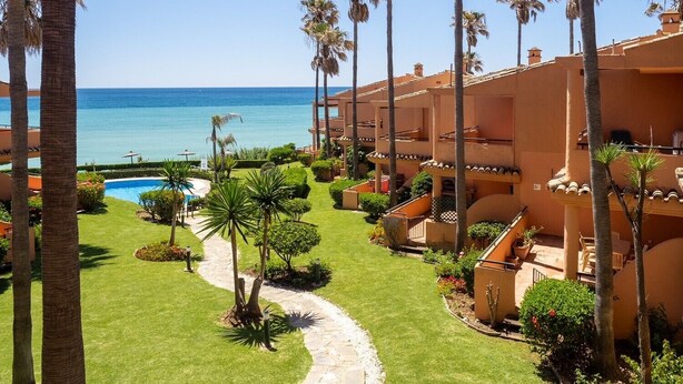 Un resort con piscina, palmeras y vista al océano.