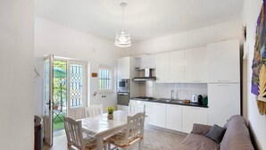 A modern kitchen with white cabinets, a dining table with chairs, a sofa, and a hanging light fixture. - Apartment 'Bella Veduta Luna' with Sea and Mountain Views, Wi-Fi, and Air Conditioning (Agerola)