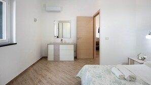 A bedroom with a bed, a dresser, a mirror, a door, and a window. - Apartment 'Bella Veduta Luna' with Sea and Mountain Views, Wi-Fi, and Air Conditioning (Agerola)