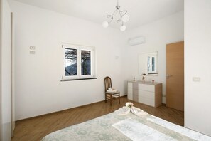 A bedroom with a bed, a window, a chair, a dresser, and a door.