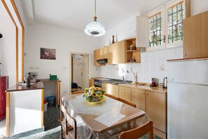 A compact kitchen with wooden cabinets, a dining table with a floral centerpiece, and a built-in oven.