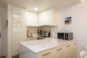 Una cocina moderna con gabinetes blancos, microondas y cafetera.