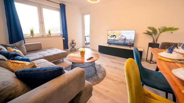 Ein modernes Wohnzimmer mit Sofa, Couchtisch und Esstisch.