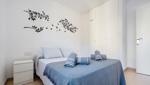 A bedroom with a bed, a nightstand, a door, and wall decorations. - Apartment 'Apartamento Ct' with Shared Pool, Wi-Fi and Air Conditioning (Salou)