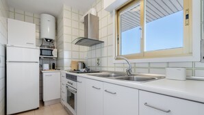 A modern kitchen with white cabinetry, a stainless steel sink, and a window above the sink. - Apartment 'Apartamento Ct' with Shared Pool, Wi-Fi and Air Conditioning (Salou)