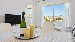 A hotel room with a dining table, a bottle of Cava Montecas, two candles, a TV, and a balcony with a view of buildings. - Apartment 'Apartamento Ct' with Shared Pool, Wi-Fi and Air Conditioning (Salou)