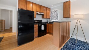 A modern kitchen with wooden cabinets, a black refrigerator, and a stove. - Good 2 Go at L Rancho Court (Spearfish)