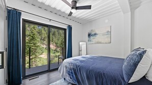 A bedroom with a large sliding glass door leading to a balcony, a ceiling fan, and a painting on the wall. - Crate Escape at Terry Peak (Lead)
