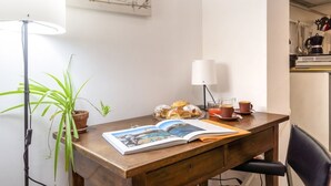 Un escritorio de madera con un libro, una lámpara, una planta en maceta y pasteles.