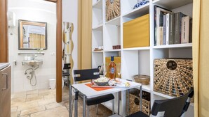 Un espacio habitable compacto con kitchenette, comedor y estantería.
