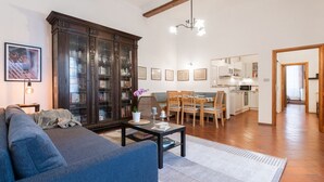 Een woonkamer met een bank, een salontafel, een kast en een eethoek met stoelen en een tafel.