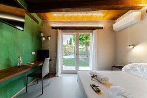 A room with a bed, a desk, a chair, a TV, and a sliding glass door to the outside. -  L’Organetto Luxury B&B - Brezza Queen Room (Alberelli)