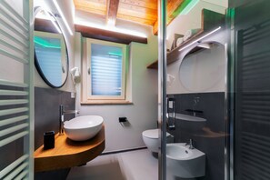 A modern bathroom with a wooden vanity, a large mirror, a white sink, a bidet, and a window with blinds. -  L’Organetto Luxury B&B - Brezza Queen Room (Alberelli)