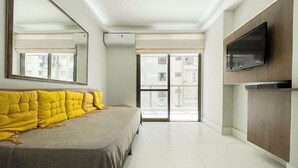 Ein modernes Schlafzimmer mit einem großen Bett, einem flachbildfernseher an der Wand und einer Glasschiebetür, die auf einen Balkon führt.