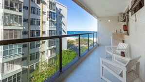 Ein Balkon mit Meerblick, weißen Stühlen und einer gefliesten Wand.