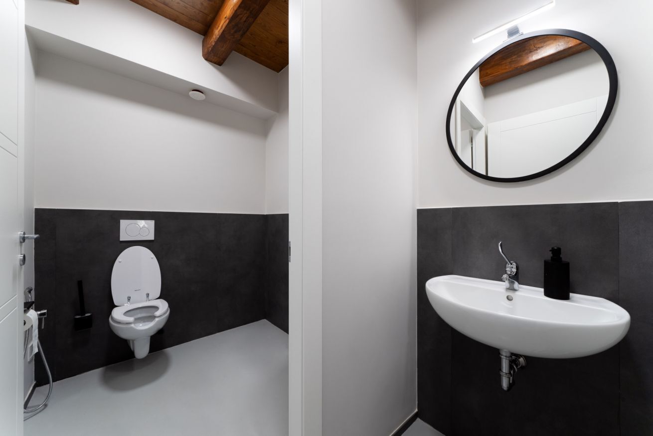 A modern bathroom with a toilet, sink, and mirror.