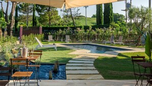 Un patio trasero con piscina, sillas de descanso y una pérgola.