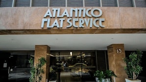 Exterior de l'edifici Atlantic Flat Service, amb un disseny modern, amb grans finestres de vidre i plantes en testos a l'entrada.