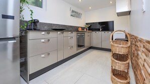 Una cocina moderna con electrodomésticos de acero inoxidable, armarios de tonos claros y suelo de baldosas.